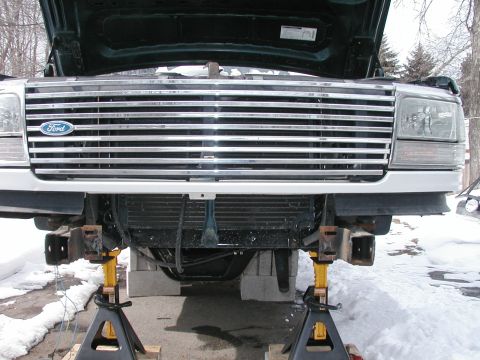 1994 Ford Bronco - Front view of a 1994 Ford Bronco's grille and headlights, supported by jack stands in a snowy environment.