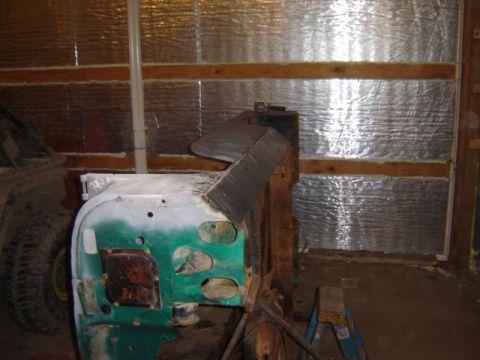 1992 Ford Bronco - The body of a Jeep CJ-6 is seen in a workshop, partially primed in white over green paint.