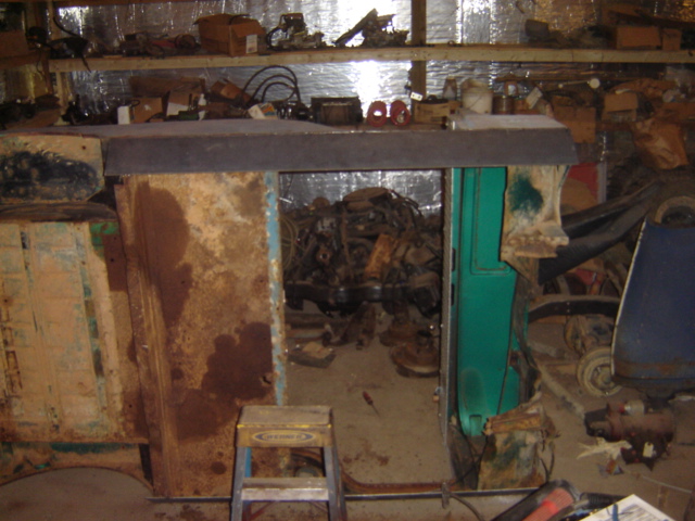 Cluttered garage interior with shelves of parts and engines visible through an opening