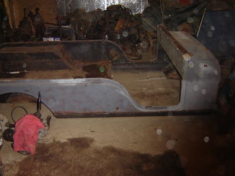 1992 Ford Bronco - A heavily rusted vehicle body section, possibly undergoing restoration, sits in a cluttered garage.