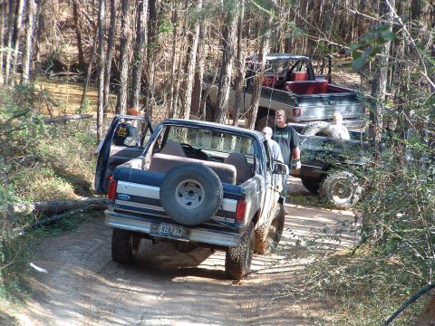 1993 Ford Bronco - A 1993 Ford Bronco is seen from the rear on a dirt path, with other off-road vehicles behind it.