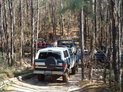 1993 Ford Bronco - Multiple vehicles, including a 1993 Ford Bronco, are seen on a trail in a forest.