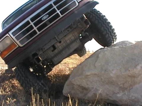1993 Ford Bronco - A maroon 1993 Ford Bronco navigates a rocky obstacle course.