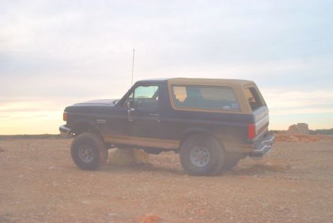 1989 Ford Bronco - This Ford Bronco is parked in a dusty, outdoor area with a hazy sky overhead.