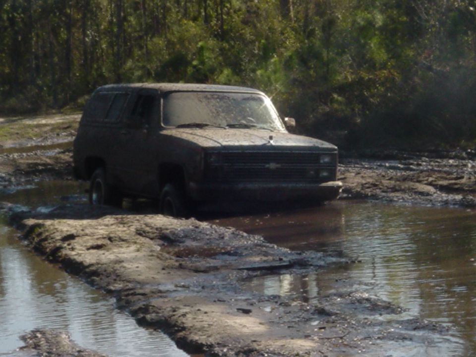 Muddy SUV stuck in water, front grille visible
