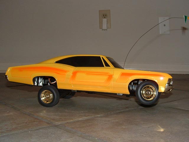 Yellow remote control car with orange racing stripes, lifted suspension, and gold rims