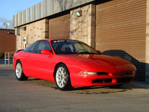 1994 Ford Probe - A red 1994 Ford Probe is parked outside a building with a large garage door.