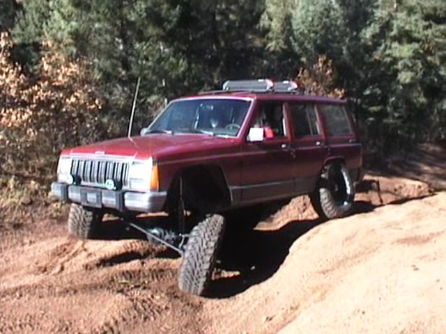 Red Jeep Cherokee XJ off-roading on a dirt trail