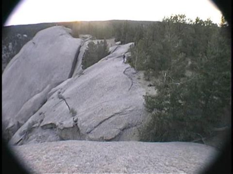 1993 Ford Bronco - A person stands on a rocky outcrop overlooking a forested area at sunset.
