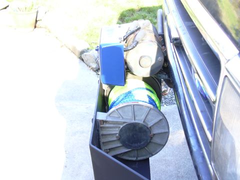 1991 Ford Bronco - A winch is mounted to the front of a vehicle, with a blue electrical box attached.