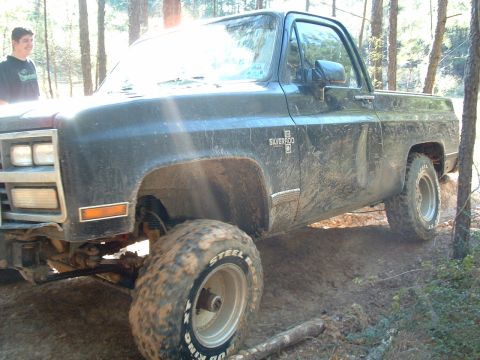 1993 Ford Bronco - This lifted Chevrolet pickup truck is covered in mud after driving on a wooded trail.
