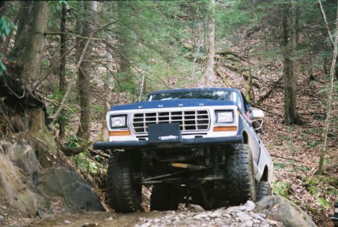 1990 Ford Bronco - This Ford Bronco navigates a rocky, wooded path, its off-road capabilities.
