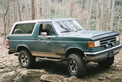 1990 Ford Bronco - This 1990 Ford Bronco navigates a challenging, rocky trail in a wooded area.