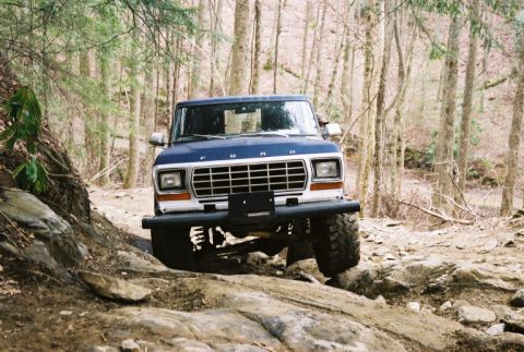 1990 Ford Bronco - Ford Bronco tackles a challenging rocky trail in a wooded area.