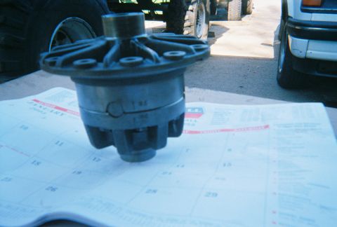 1978 Ford Bronco - A differential part rests on a calendar, with parts of vehicles visible in the background.