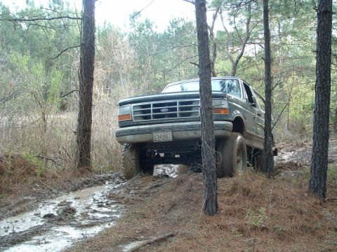 1993 Ford Bronco - A Ford Bronco navigates a muddy, wooded path.
