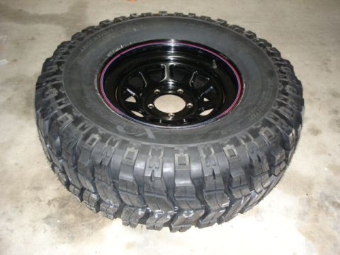 1987 Ford Bronco - A close-up view of a single off-road tire and rim assembly.