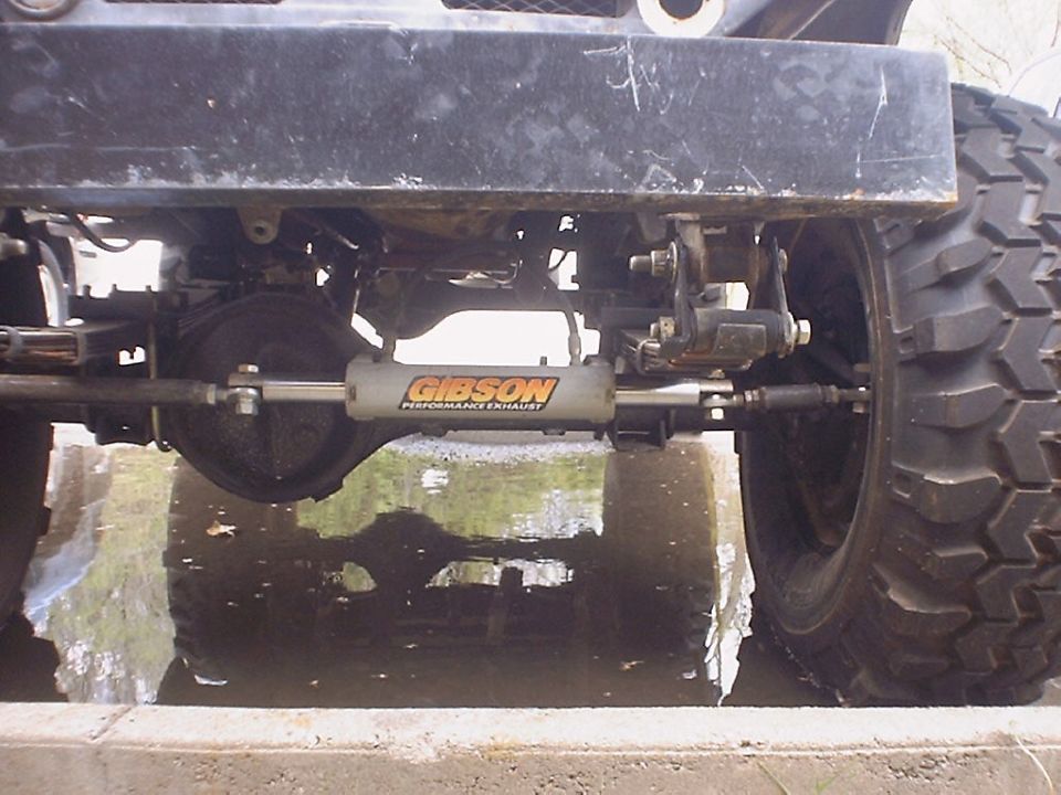 Underside of a truck showing axle and a Gibson Performance Exhaust steering stabilizer