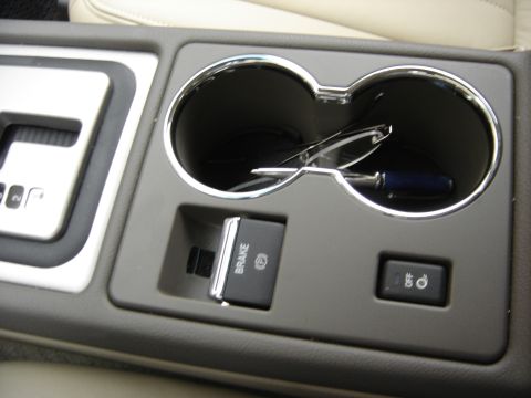 2002 Lincoln Town Car - The interior of a vehicle shows the center console, cupholders, a gear shifter, and an electronic parking brake button.