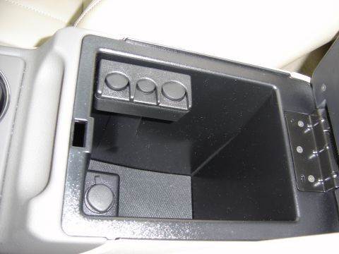 2002 Lincoln Town Car - The interior of the vehicle shows an open center console with a power outlet and storage space.