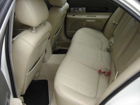 2002 Lincoln Town Car - The interior of a car shows the rear seating area and door panel with tan leather upholstery.