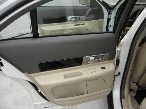 2002 Lincoln Town Car - The interior door panel of a white car shows beige and gray upholstery with chrome accents.