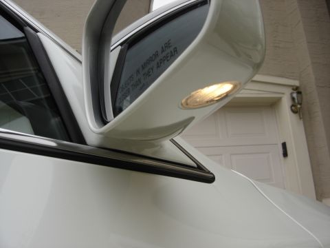 2002 Lincoln Town Car - A close-up view of a white car's side mirror and door panel, with a reflection of a garage door.
