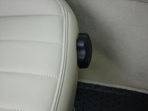 2002 Lincoln Town Car - Close-up of a black seat adjustment knob on light-colored, tufted upholstery inside a vehicle.