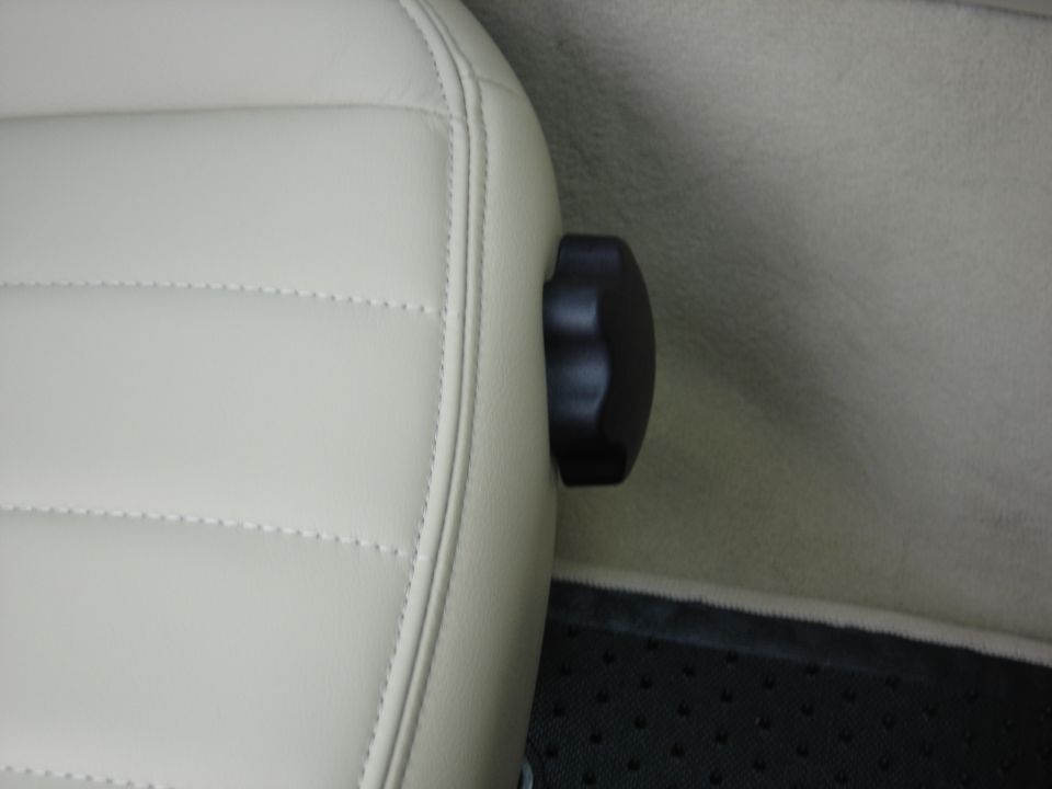 Interior seat adjustment knob on light-colored upholstery