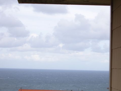 1988 Ford Bronco - A cloudy sky hangs over a choppy ocean, viewed from a balcony with a partial structure visible below.