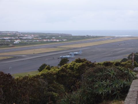 1988 Ford Bronco - Two military transport planes are parked on an airport tarmac, with a coastal town visible in the distance and the ocean beyond.