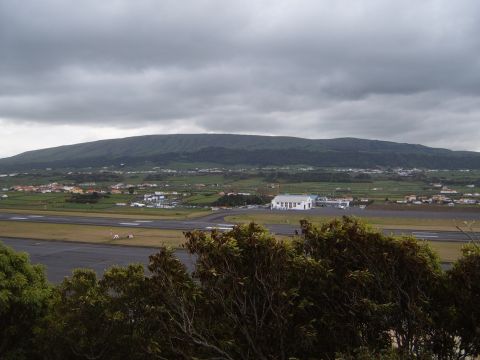 1988 Ford Bronco - A wide view of an airport with a town and a mountain in the background on a cloudy day.