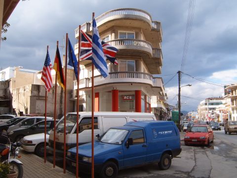 1988 Ford Bronco - Flags fly in front of a building on a street with several parked vehicles and traffic.