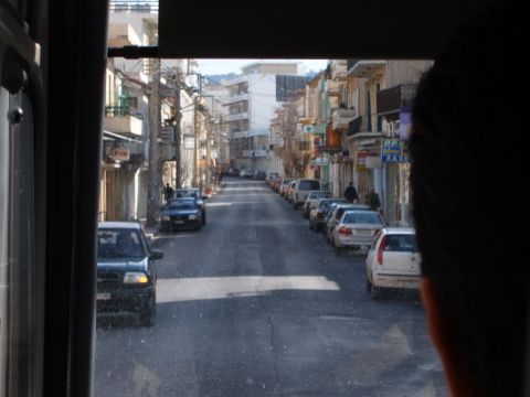 1988 Ford Bronco - A view down a street in a town, with cars parked on both sides and buildings lining the road.
