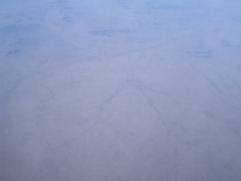 1988 Ford Bronco - An aerial perspective reveals a desolate desert expanse, marked by subtle trails across its dry surface.