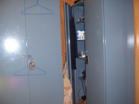 1988 Ford Bronco - Interior view of blue metal storage cabinets with items on shelves and a drawn hanger.