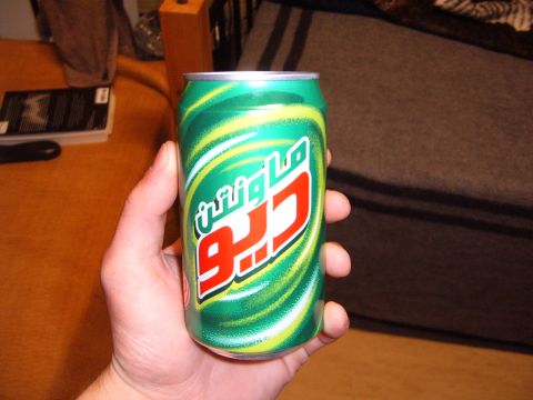 1988 Ford Bronco - A hand holds a can of Mountain Dew with distinctive green and yellow swirls and Arabic script.
