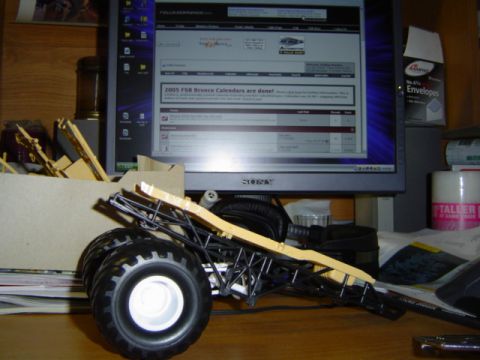 1979 Ford Bronco - Model car chassis with large tires and unfinished body parts sits on a desk.