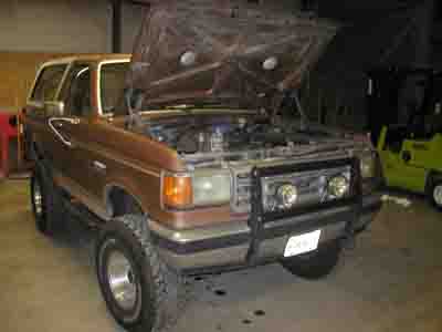 1988 Ford Bronco - Brown Ford Bronco with hood open, engine visible, bull bar on front.