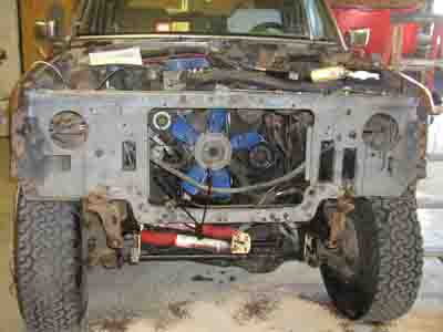 1988 Ford Bronco - The front of a Ford Bronco is shown with the grille and hood removed, revealing the engine bay.