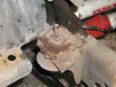 1988 Ford Bronco - This photo shows a close-up view of a vehicle's engine mount, with some red and white cylindrical objects visible in the background.