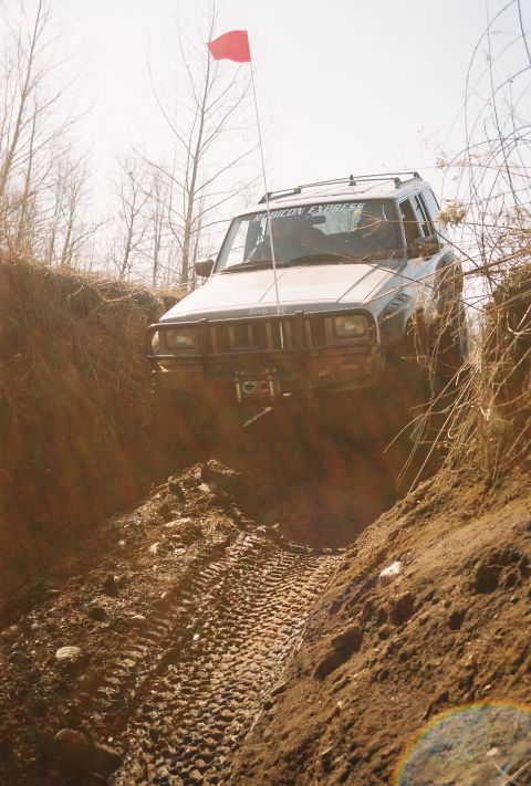 1995 Ford Bronco - A Jeep Cherokee XJ navigates a challenging muddy off-road course.