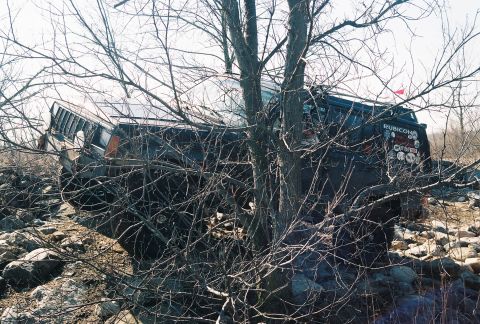 1995 Ford Bronco - Off-road vehicle appears stuck in trees and rocks, with a 'Rubicon' sticker visible on the rear.