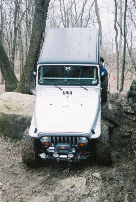 1995 Ford Bronco - A Jeep Wrangler tackles a challenging off-road course with steep inclines and rough terrain.