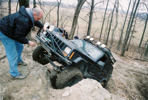 1995 Ford Bronco - A heavily modified Jeep Cherokee XJ navigates a challenging off-road trail with assistance from a spotter.