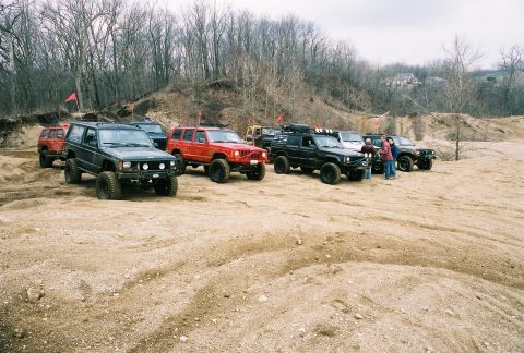 1995 Ford Bronco - A group of modified SUVs are gathered on a sandy terrain, suggesting an off-road excursion or event.