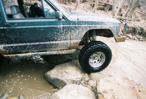 1995 Ford Bronco - A Jeep Cherokee XJ navigates a rocky stream bed during an off-road excursion.