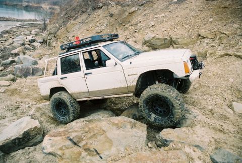 1995 Ford Bronco - This modified Jeep Cherokee is shown tackling a challenging off-road course with large rocks.