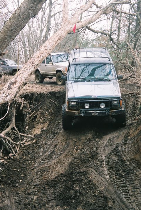 1995 Ford Bronco - Multiple Jeep Cherokee XJs navigate a challenging muddy off-road trail.