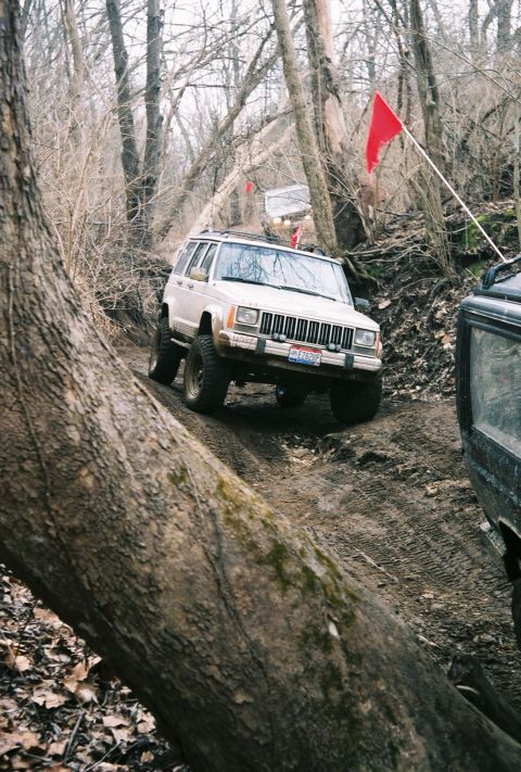 1995 Ford Bronco - A group of off-road vehicles navigates a challenging, wooded trail during an event.